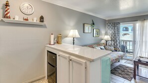 A compact kitchen with a built-in dishwasher, a small dining area with a table and chairs, and a balcony with a view.