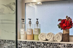 A bathroom shelf with toiletries, towels, and a vase with flowers. - Ideally Located West Palm Beach Apartment! (West Palm Beach)