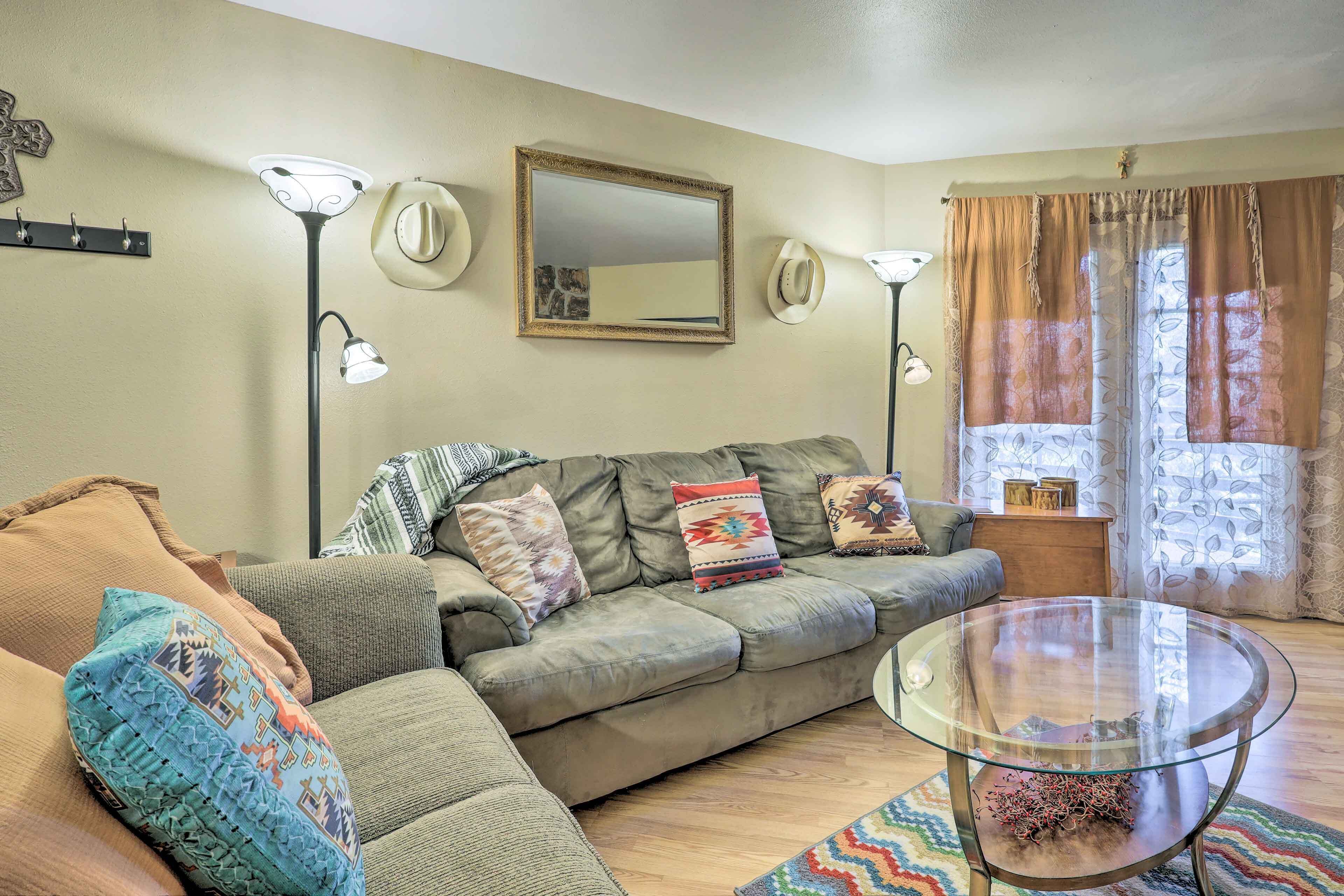 A living room with a sofa, a glass coffee table, and a lamp.