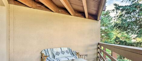 Un espacio de estar al aire libre cubierto, con un banco de madera y un sofá acolchado.