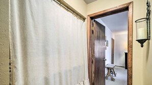 A hallway with a wooden door, a white curtain, and a small table with a lamp.