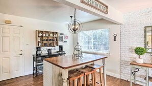 A kitchen with a central island, wooden stools, a hanging light fixture, a coffee station, and a brick wall. - 1 Mi to Main Street Sutter Creek: Poolside Oasis! (Sutter Creek)