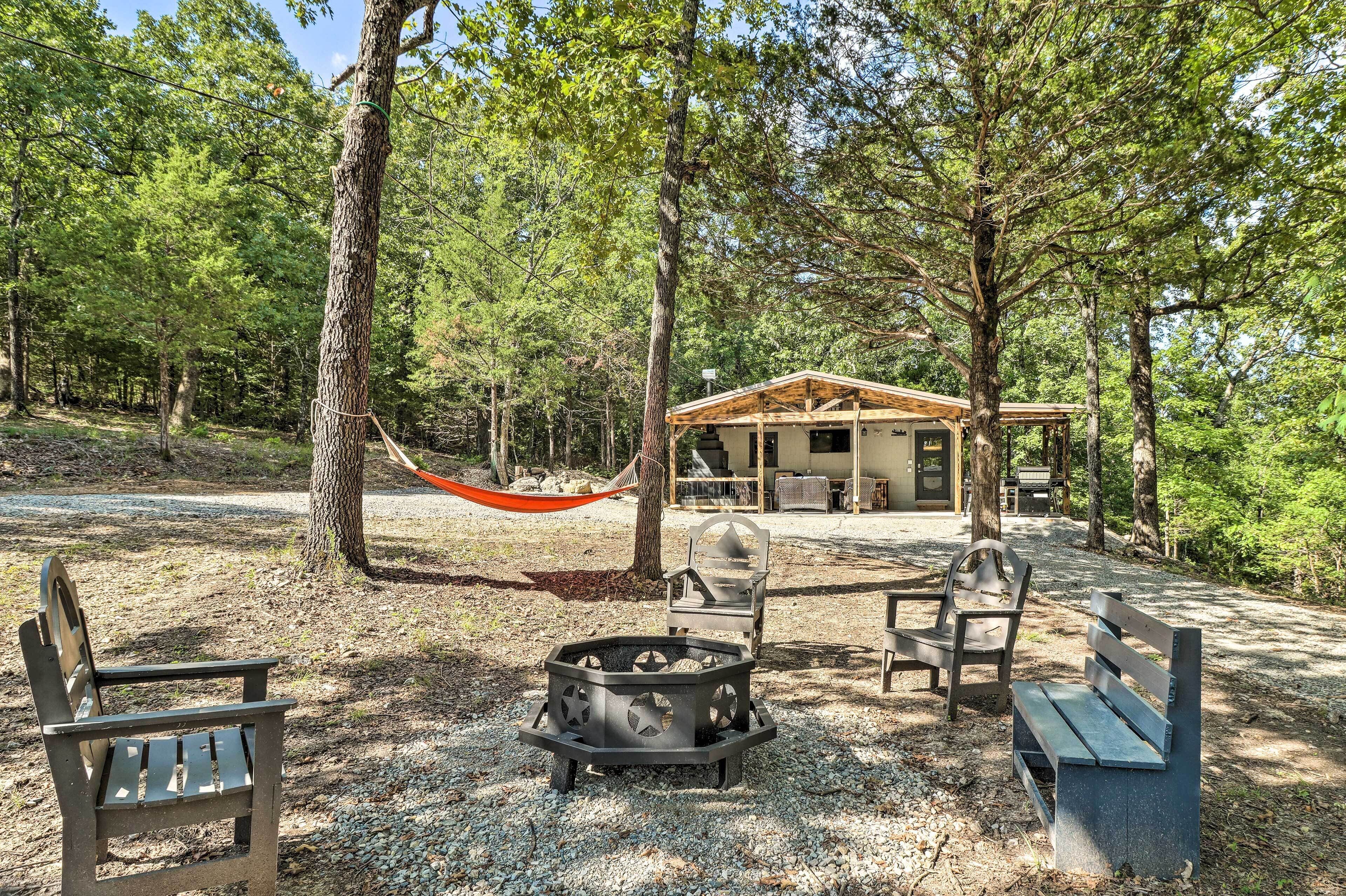 Un terrain de camping équipé d’un foyer, de bancs et d’un hamac.