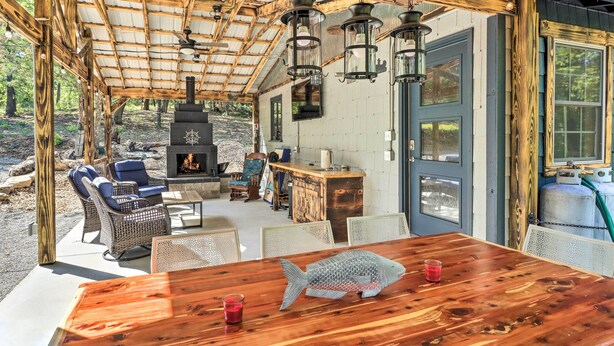A rustic wooden cabin with a fireplace, outdoor seating, and a large fish decoration on the table. - Remodeled Cabin w/ Fire Pit on Norfork Lake! (Elizabeth)