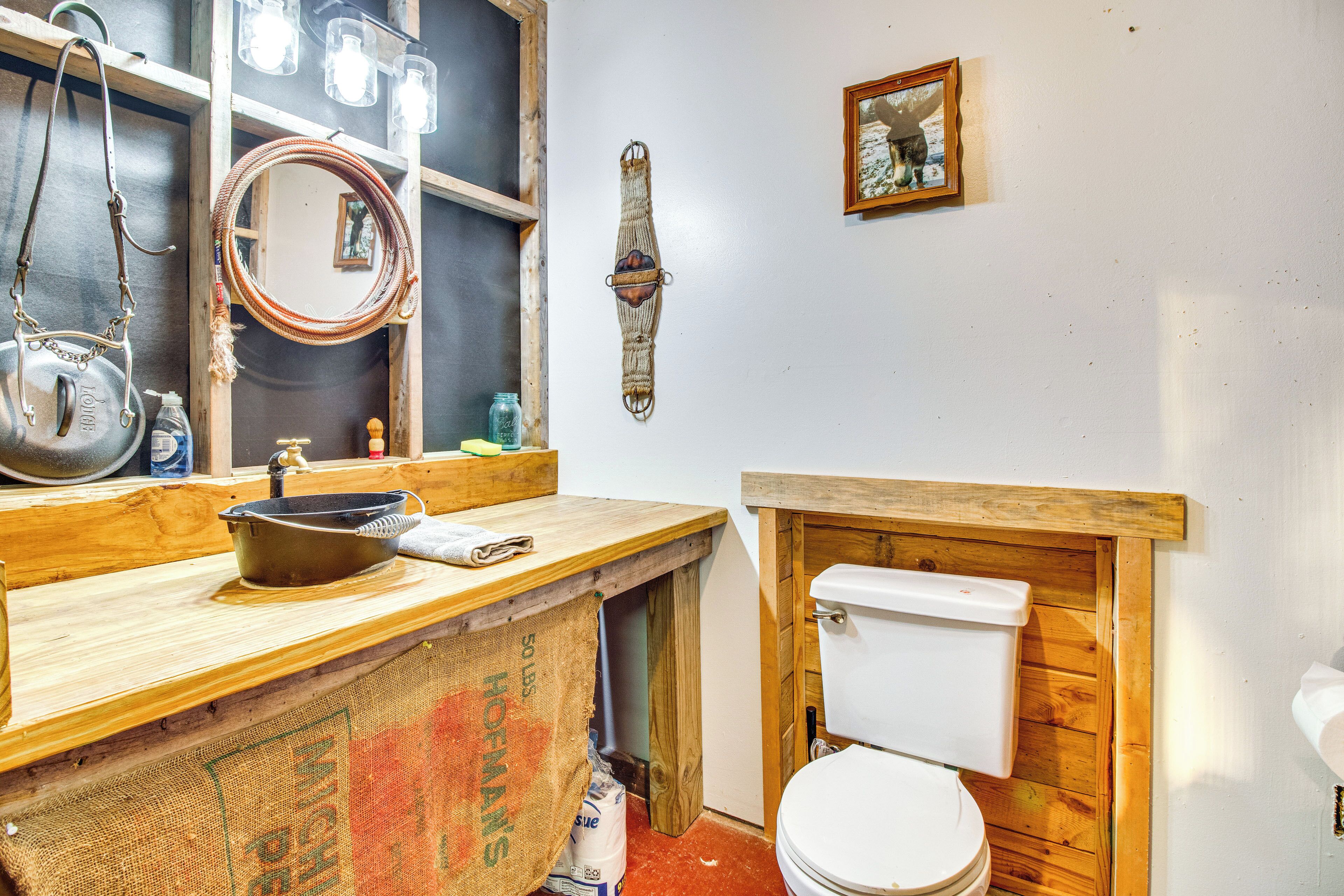 A rustic bathroom with a wooden vanity, a white toilet, and a mirror.
