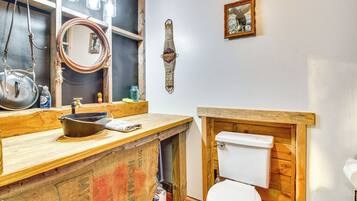 A rustic bathroom with a wooden vanity, a white toilet, and a mirror.