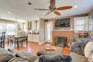 A spacious living area with a fireplace, a dining area with a wooden table and chairs, and a ceiling fan.
