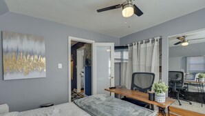 Une chambre à coucher comprenant un lit, un bureau, une chaise et un ventilateur de plafond.