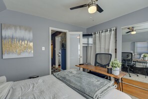 A bedroom with a bed, desk, chair, and ceiling fan.