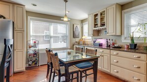 Une cuisine avec une table à manger au plateau en verre, des chaises en osier, des meubles de couleur beige et un réfrigérateur encastré.