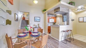 A dining area with a round table, wicker chairs, and a bar with stools.