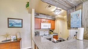 A kitchen with granite countertops, wooden cabinets, a microwave, and a stove.