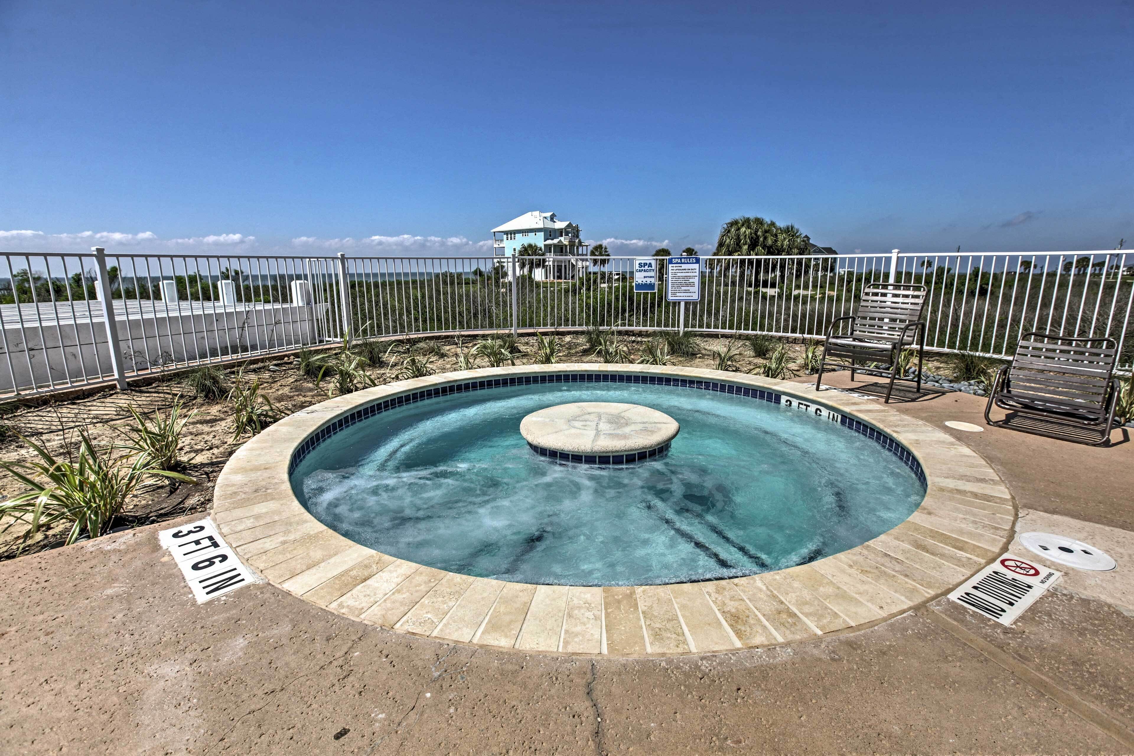 Ein kreisförmiger Pool mit einem Whirlpool in der Mitte, umgeben von einem Sandbereich und einem Metallzaun.