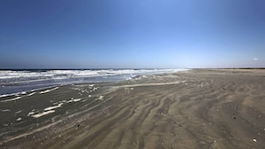 Una playa arenosa con olas suaves y cielo despejado.