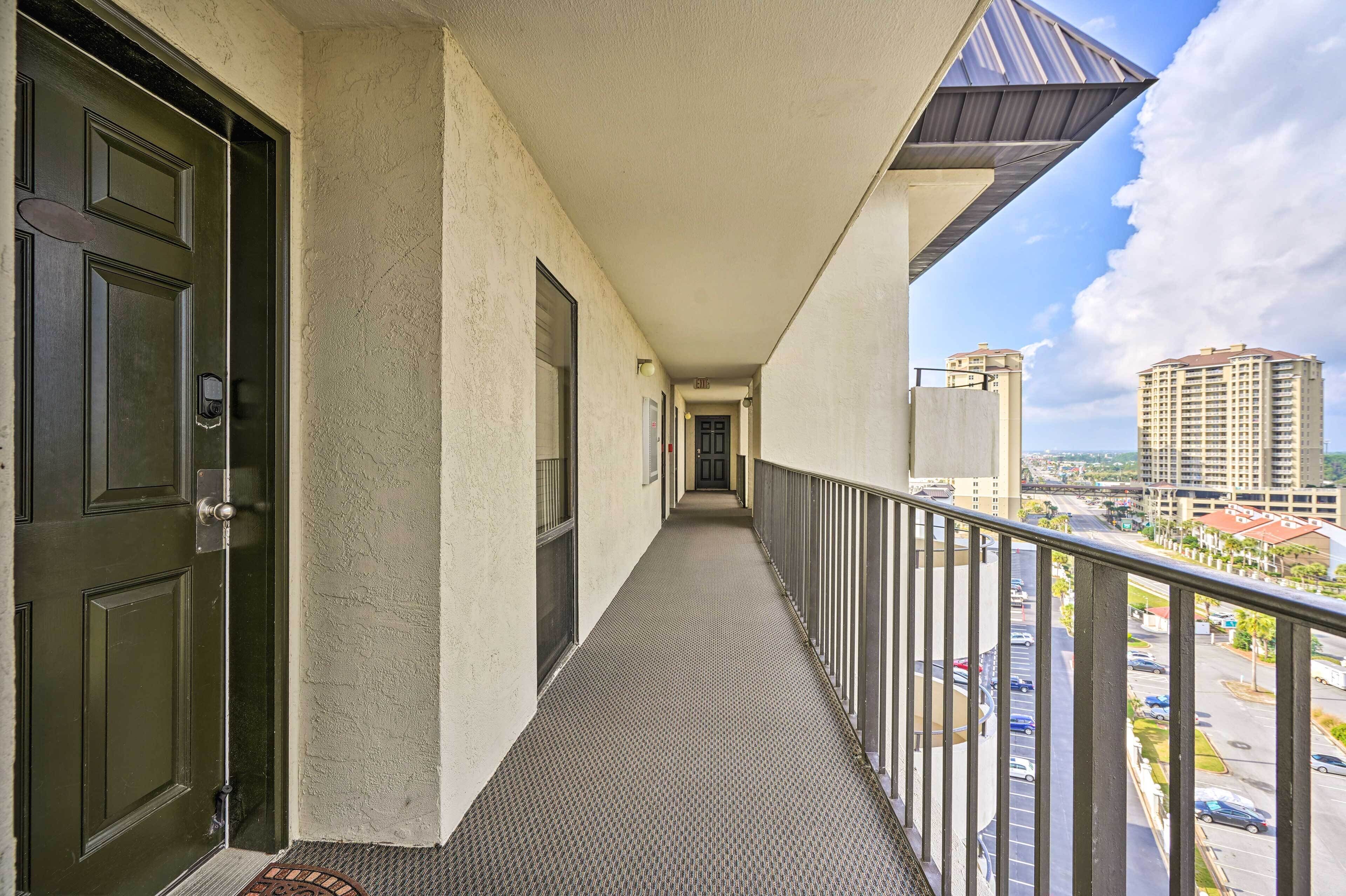 A corridor with a balcony overlooking a parking area and buildings.