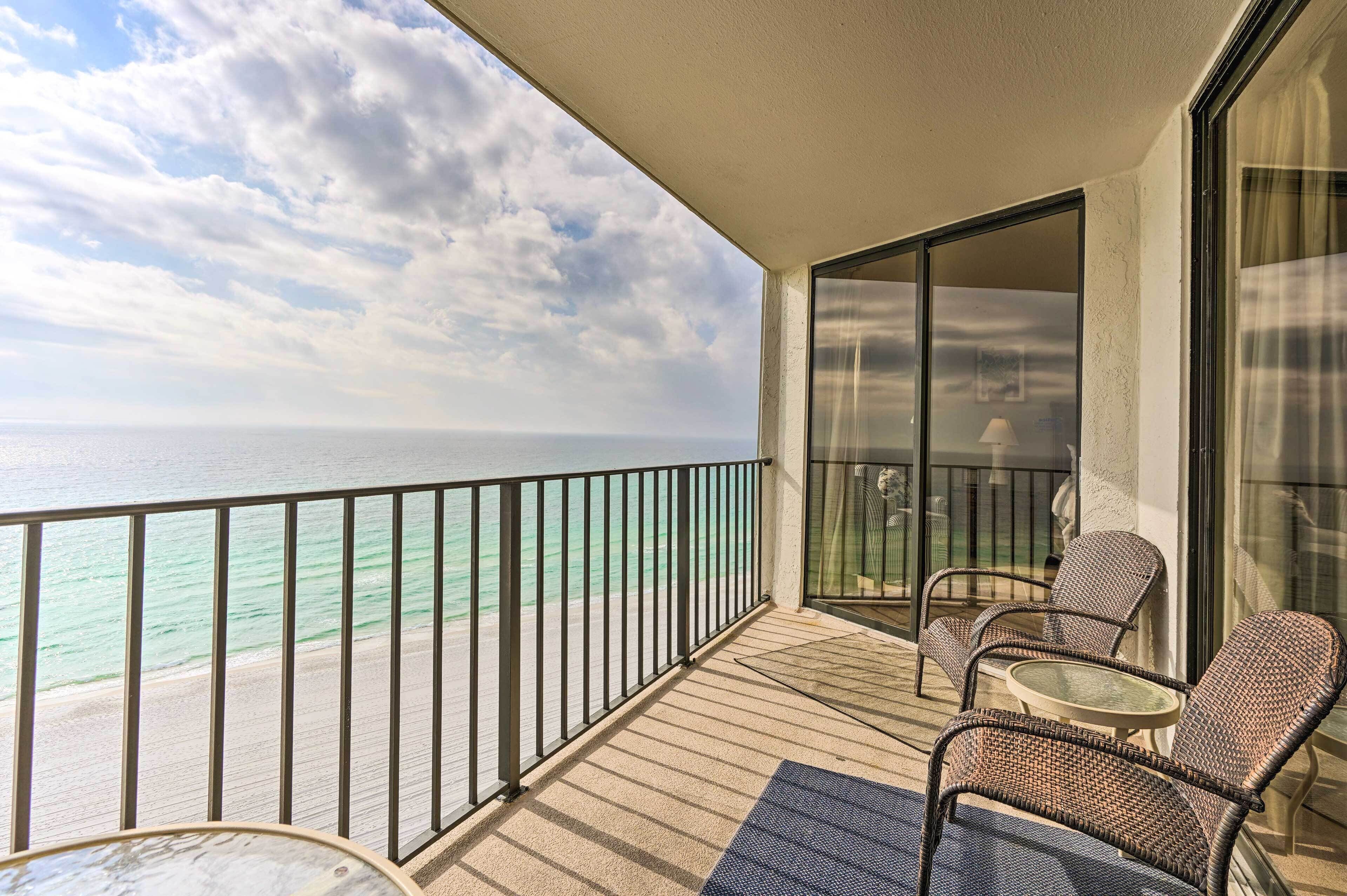 A balcony with wicker furniture, a glass door, and a view of the ocean.