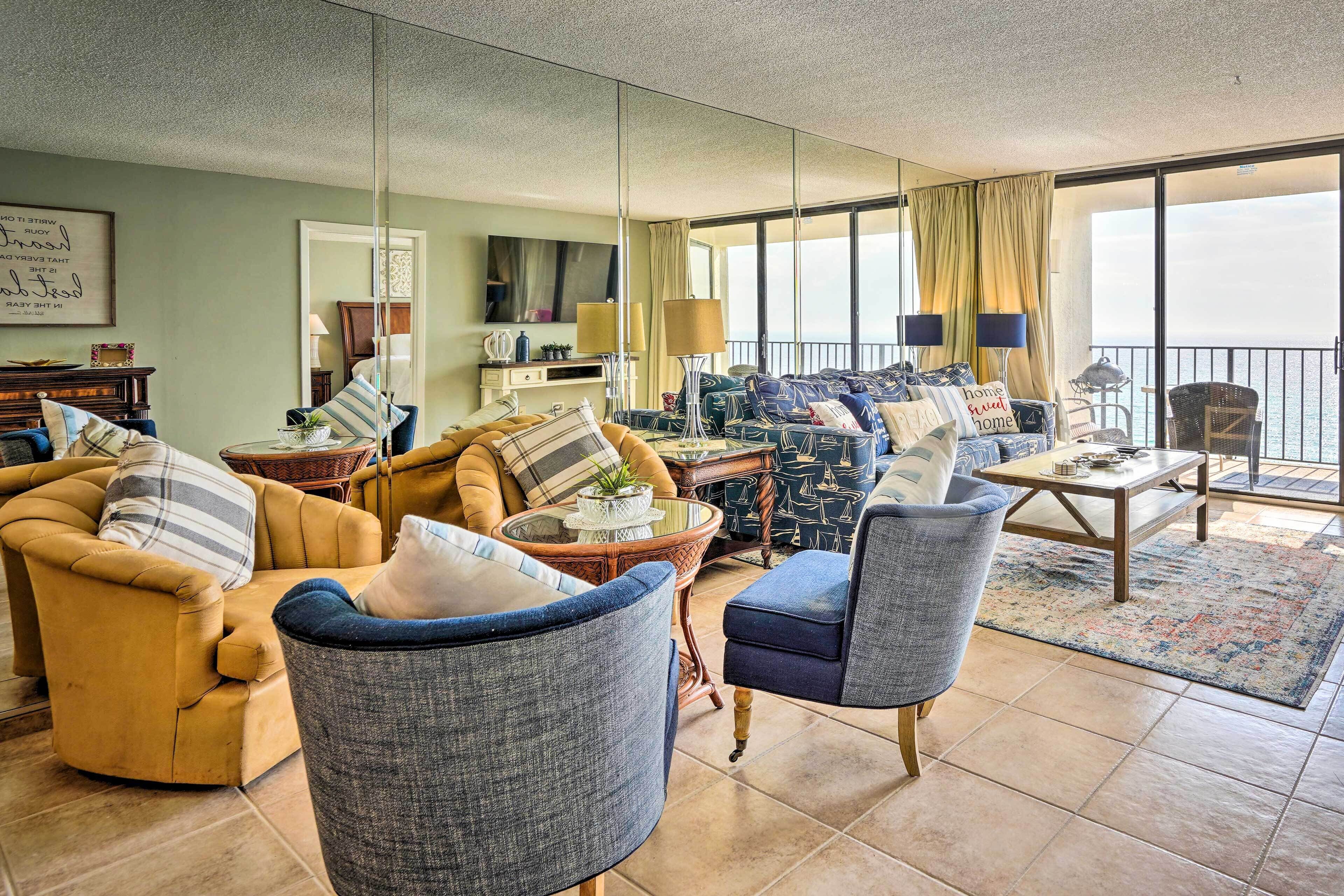 A spacious living room with a large window, a sofa set, a coffee table, and a TV.