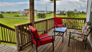 Een overdekt terras buiten met houten leuningen, een tafel en twee stoelen.