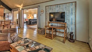 A spacious living room with a wooden TV stand, leather chairs, and a tiled coffee table. - 1/2 Mi to Beach: Canal-front Galveston Home! (Galveston)