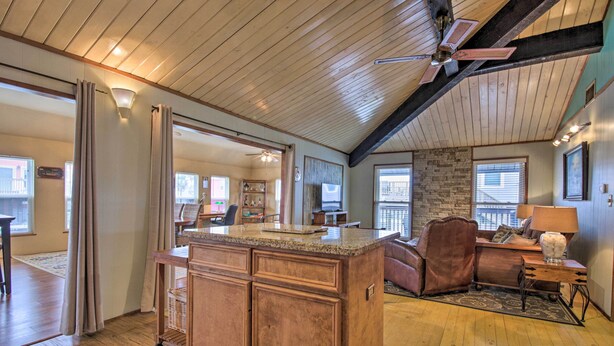A spacious living area with a wooden ceiling, a large island with a granite countertop, and a cozy seating area with a leather couch and a fireplace. - 1/2 Mi to Beach: Canal-front Galveston Home! (Galveston)