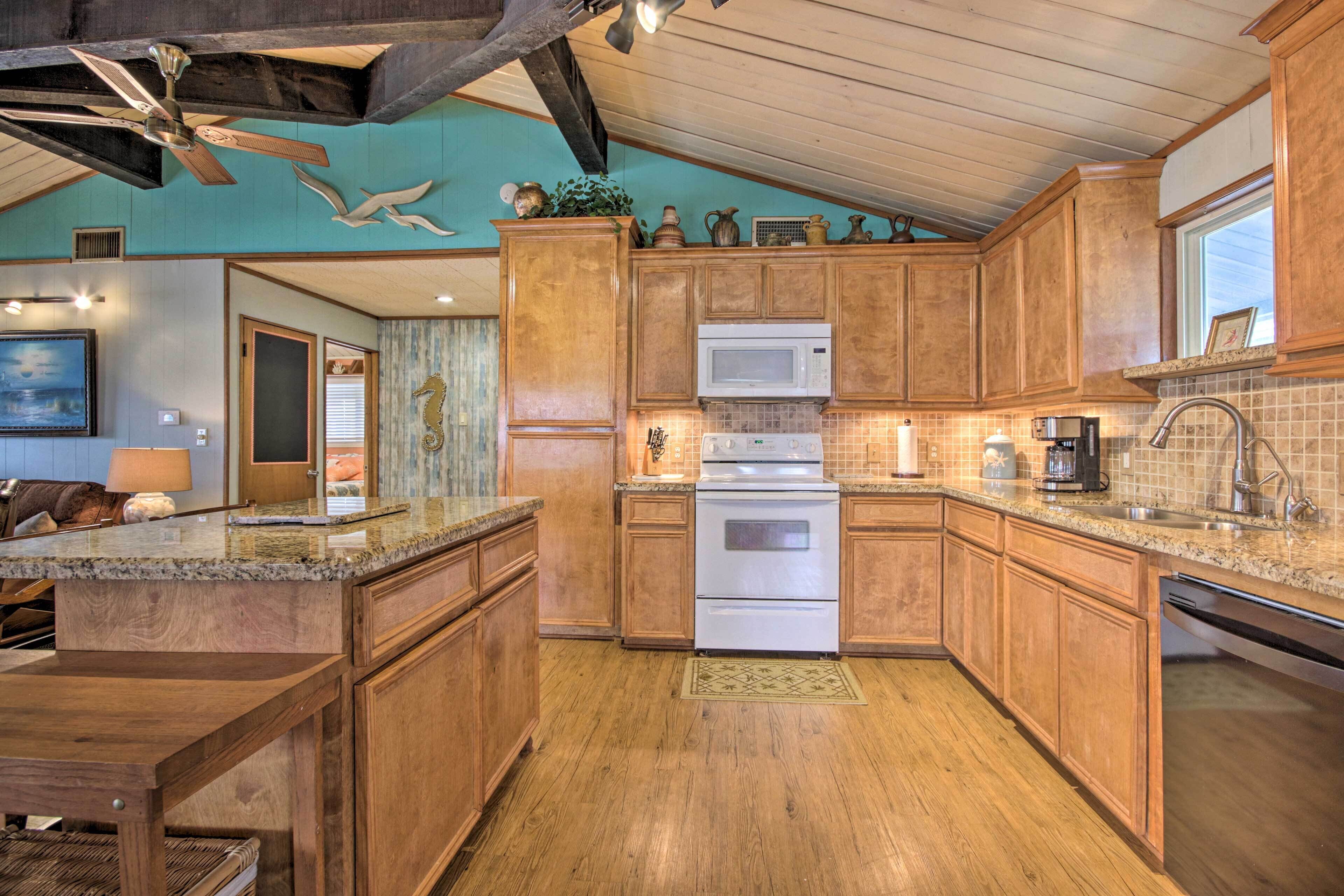 A spacious kitchen with wooden cabinets, a granite countertop, a built-in microwave, and a stainless steel sink.