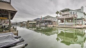 A waterfront property with docked boats, a pier, and a house with a balcony. - 1/2 Mi to Beach: Canal-front Galveston Home! (Galveston)