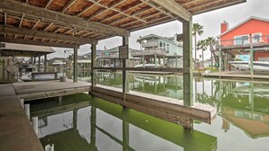 A covered dock area with wooden structures and a view of buildings across the water. - 1/2 Mi to Beach: Canal-front Galveston Home! (Galveston)