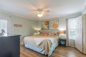 A bedroom with a bed, a ceiling fan, artwork on the wall, a nightstand, and a window with blinds. - Walk to Galveston Beach: Coastal Escape w/ Yard (Galveston)