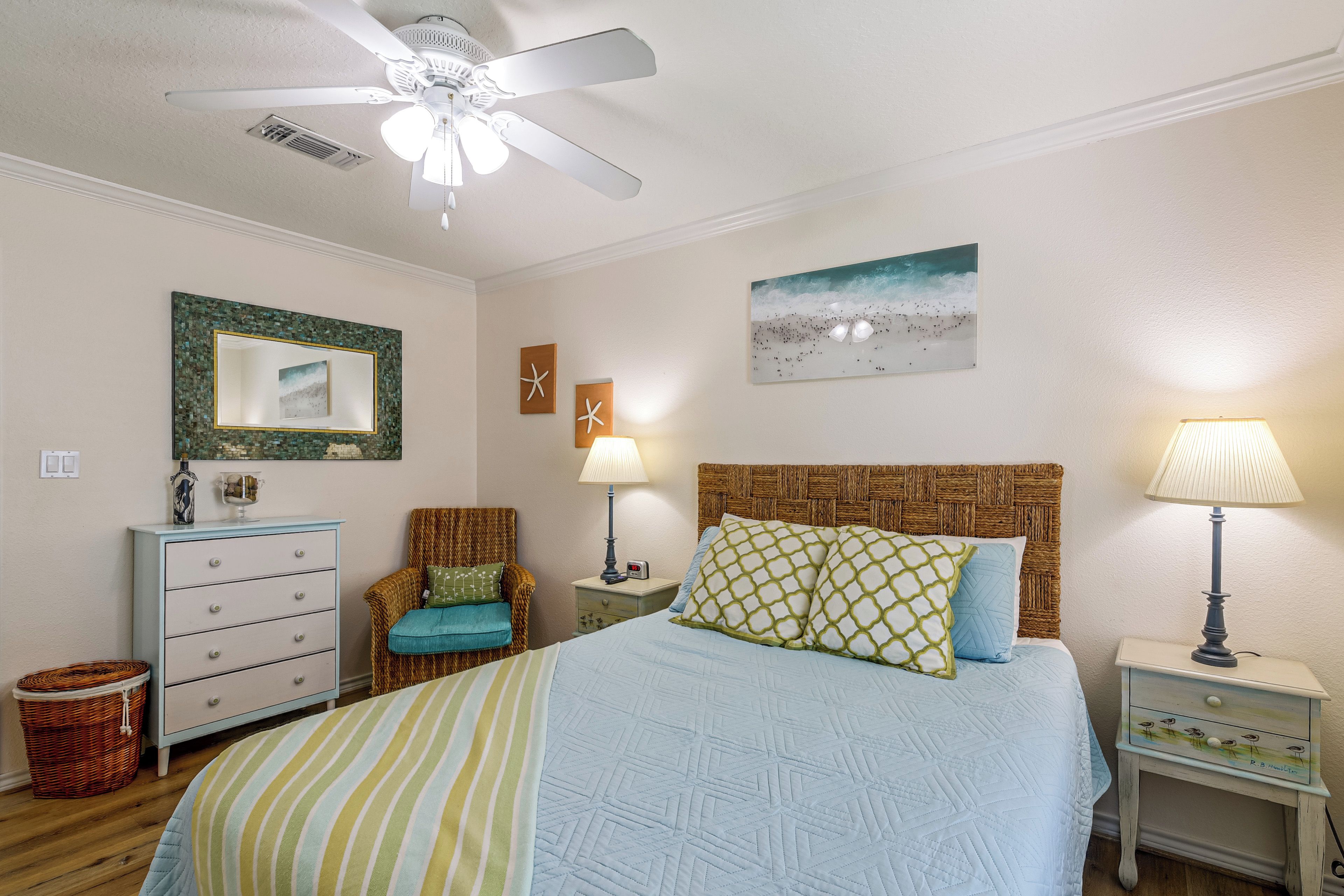 A bedroom with a bed, two nightstands, a dresser, a chair, and a ceiling fan.