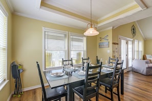 A dining area with a table set for four, chairs, and a hanging light fixture.