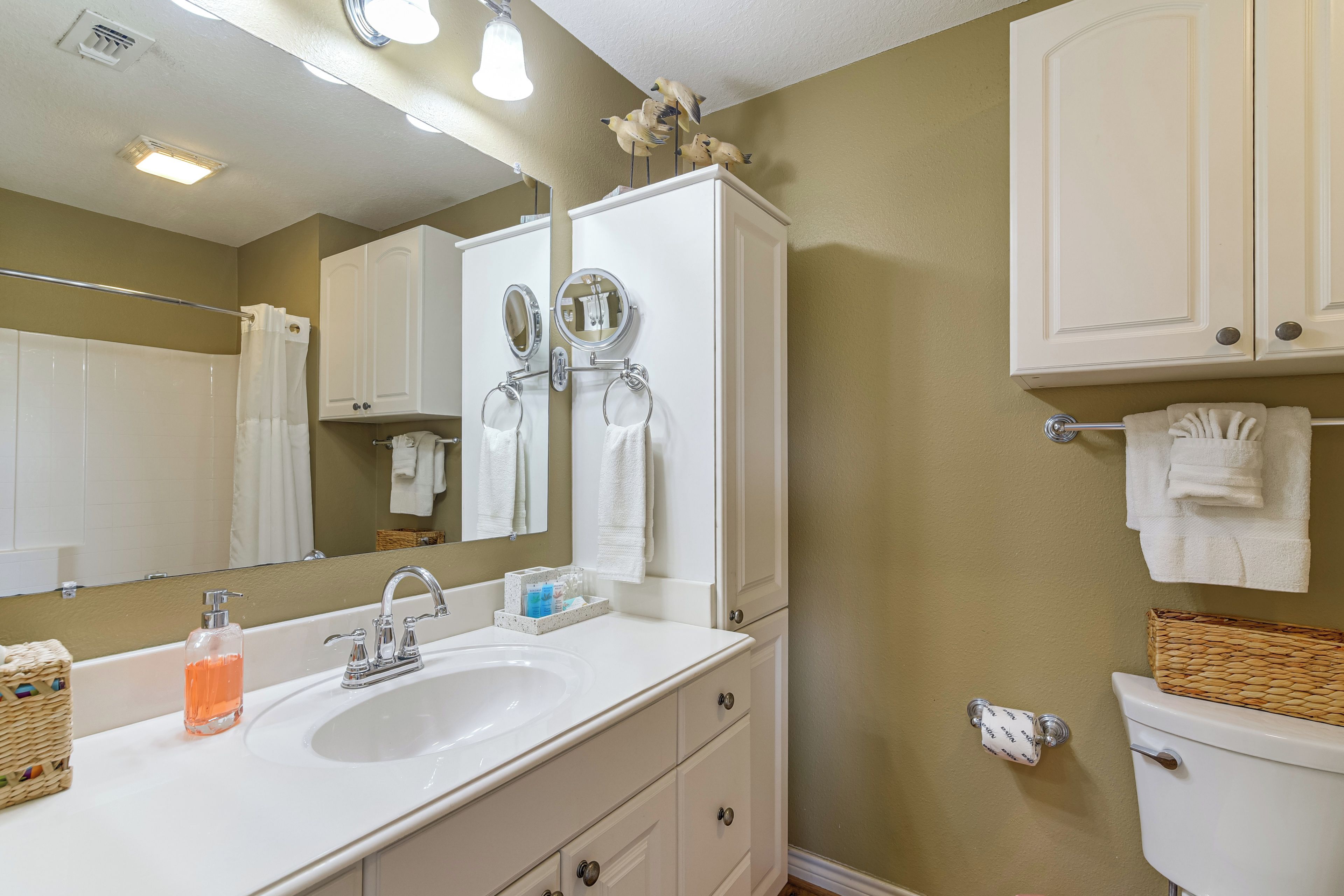 A bathroom with a white sink, two mirrors, a toilet, and a towel rack.
