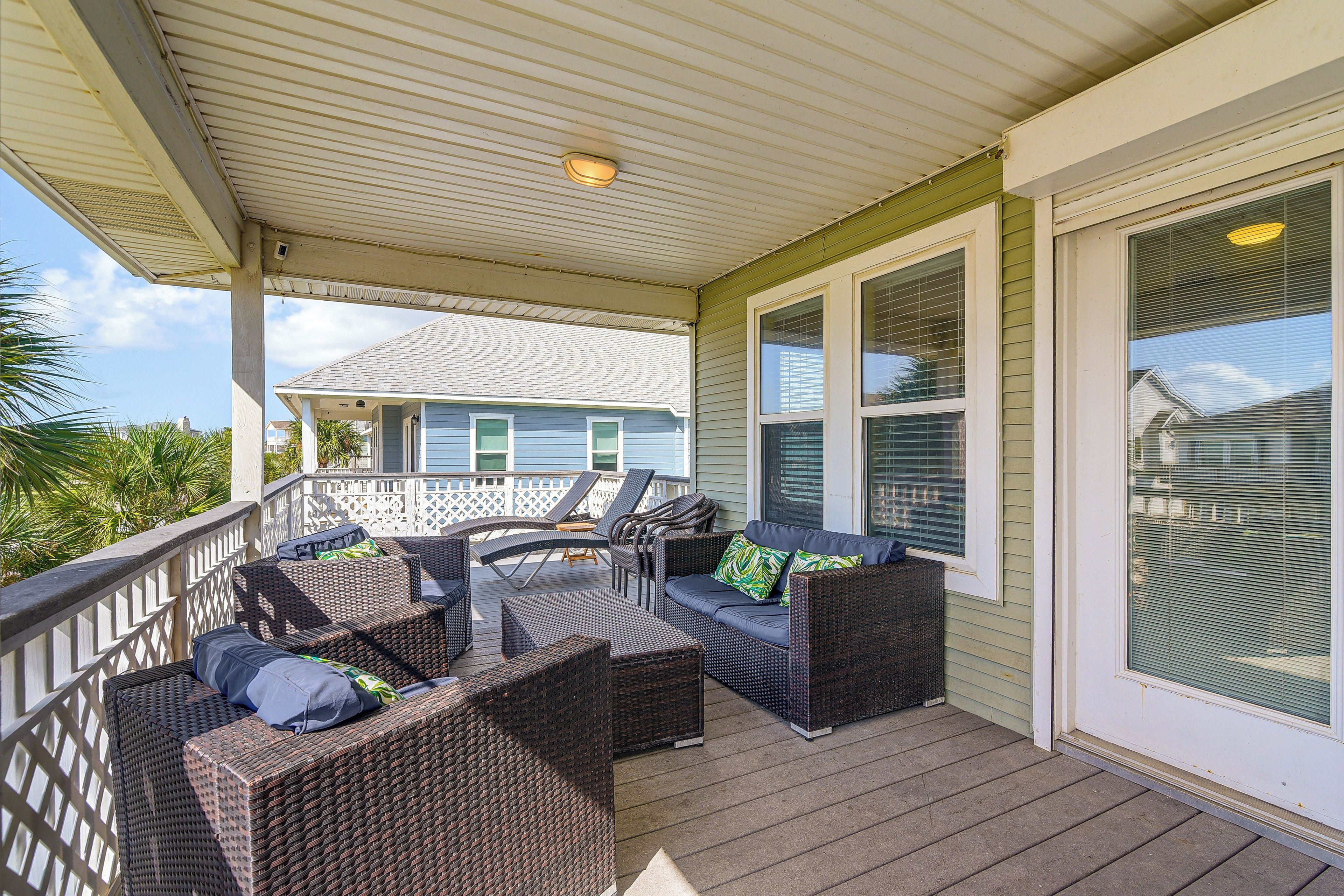 A covered porch with wicker furniture and a view of a house.