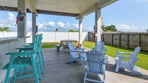 An outdoor patio with Adirondack chairs and a picnic table. - Walk to Galveston Beach: Coastal Escape w/ Yard (Galveston)