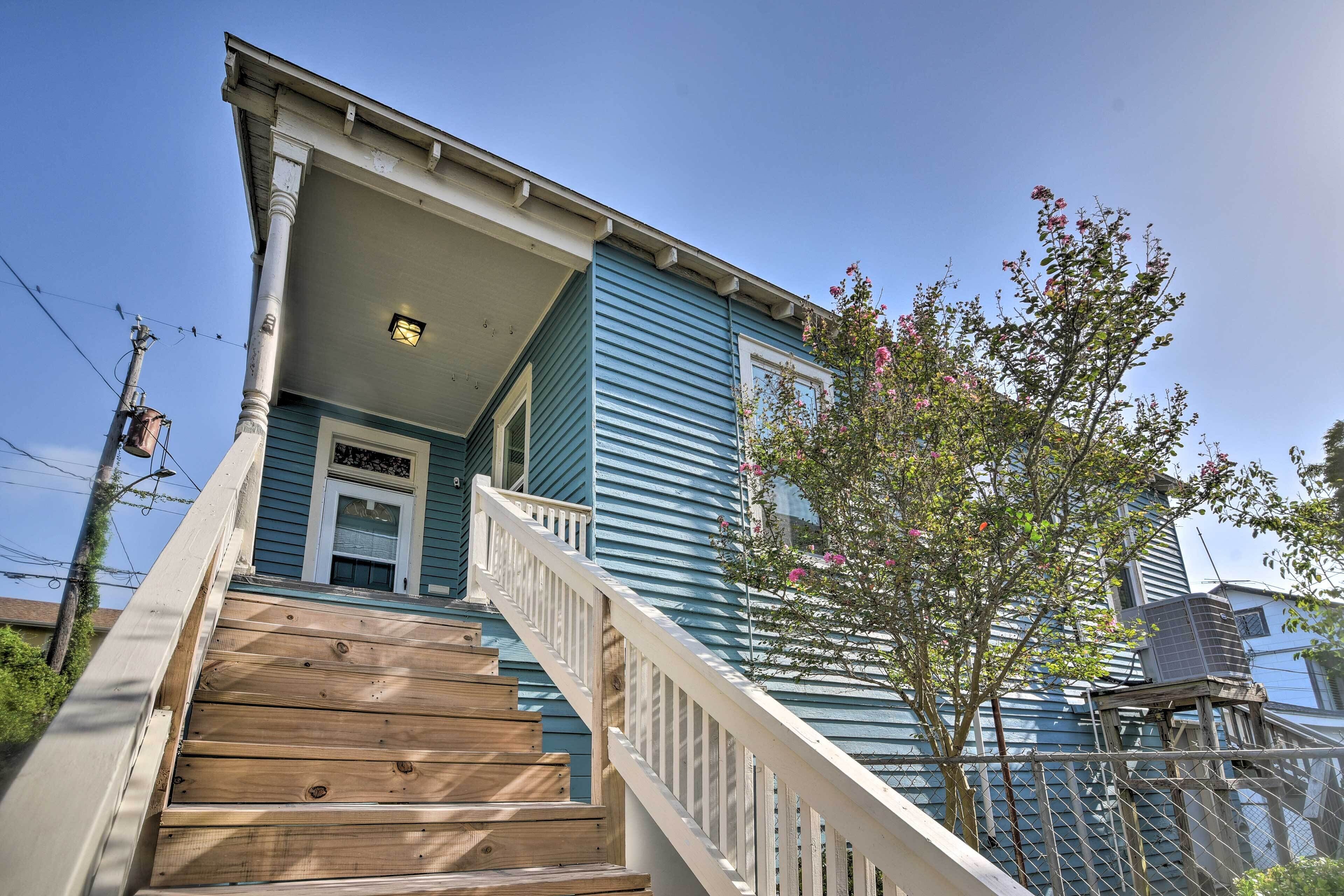 A two-story house with a wooden staircase leading to a front door.