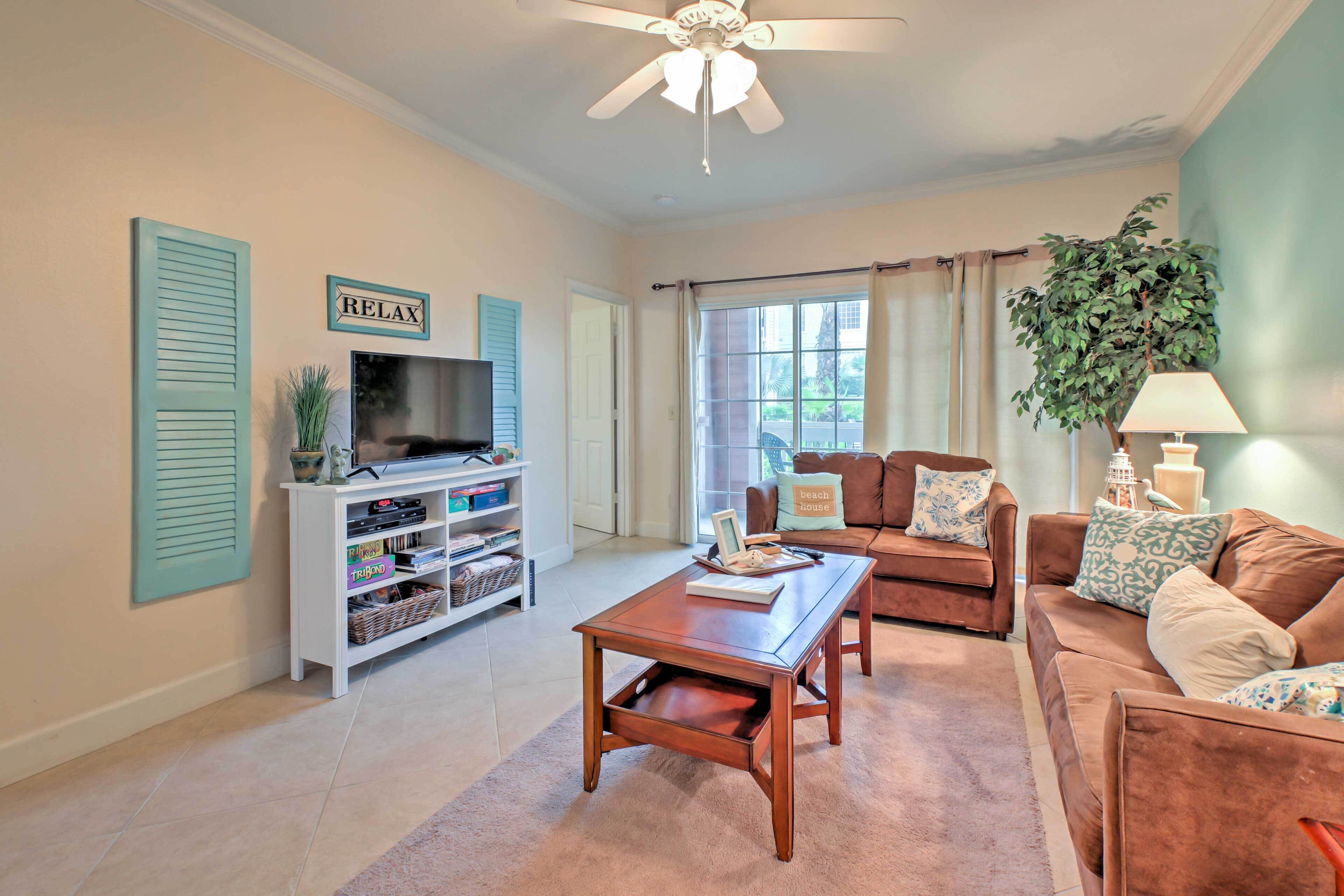 A living room with a television, a coffee table, a sofa, and a ceiling fan.