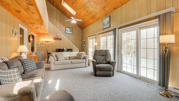 A spacious living room with a high ceiling, wooden walls, and large windows. - Near Hiking & Skiing: Home in Wilmington! (Wilmington)