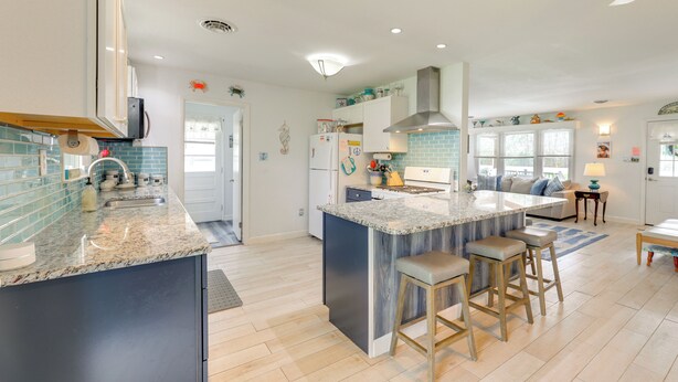 A modern kitchen with a central island, bar stools, and a dining area with a table and chairs. - Families w/ Pets! Home 4 Mi to Ocean City Beach (Berlin)