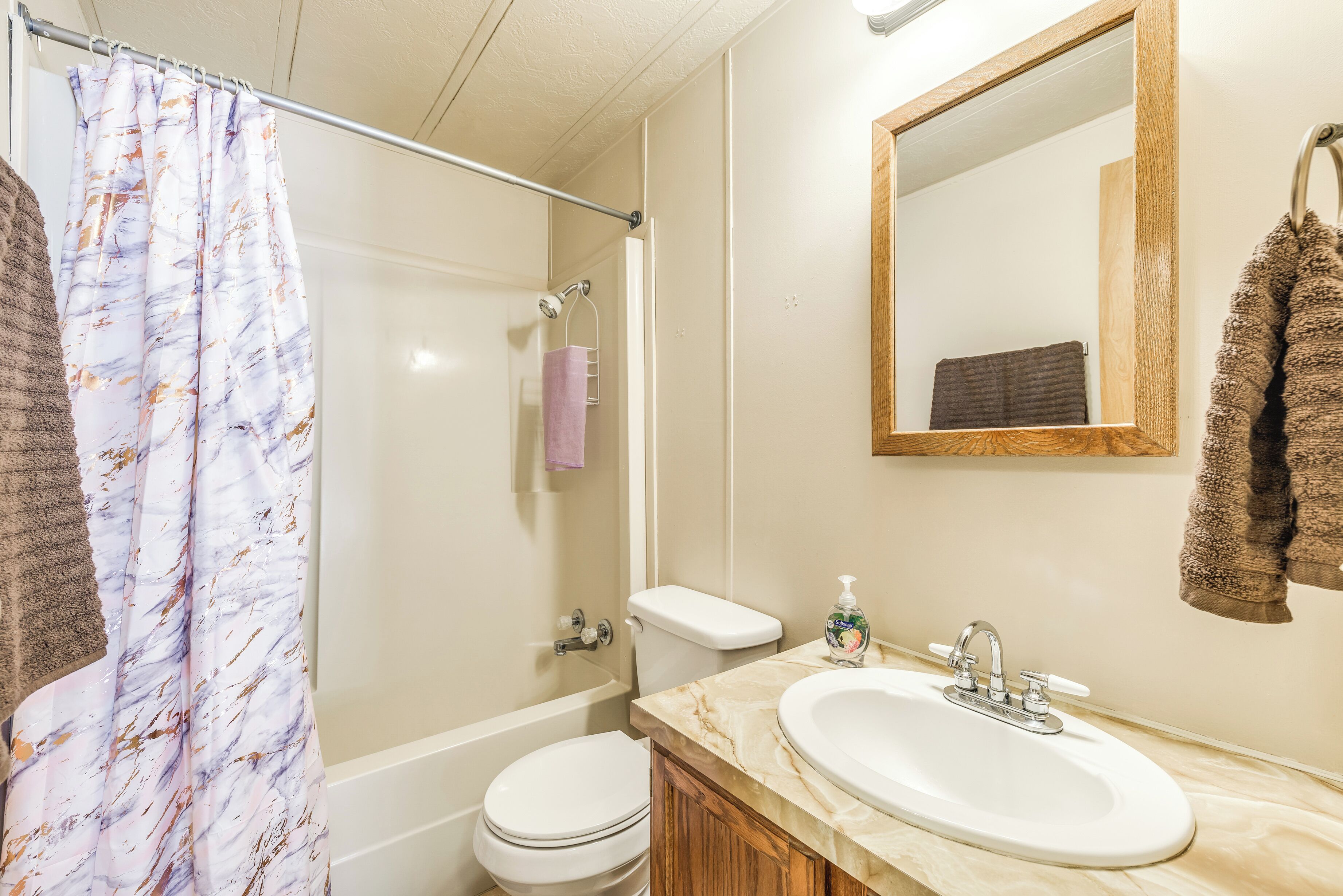 A bathroom with a shower, toilet, sink, and mirror.