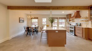A spacious kitchen with wooden beams, a dining area with chairs, and a large island. - 6 Mi to Dtwn Austin: Home w/ Screened Porch & Yard (Austin)