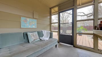Una stanza con un divano azzurrognolo, una mappa del mondo appesa al muro e vista sul giardino attraverso un'ampia finestra.