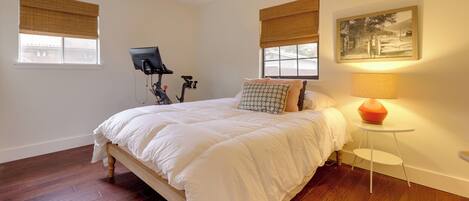 A bedroom with a bed, a ceiling fan, a lamp, and a bicycle.