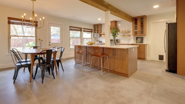 A spacious kitchen with a central island, wooden cabinets, and a dining area with chairs. - 6 Mi to Dtwn Austin: Home w/ Screened Porch & Yard (Austin)