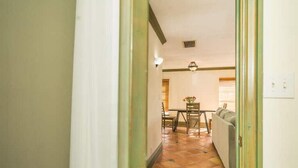 A hallway leading to a dining area with a table and chairs, a sofa, and a ceiling vent. - 2Bed/2Bath Villa by Golf Course (Lake Worth)