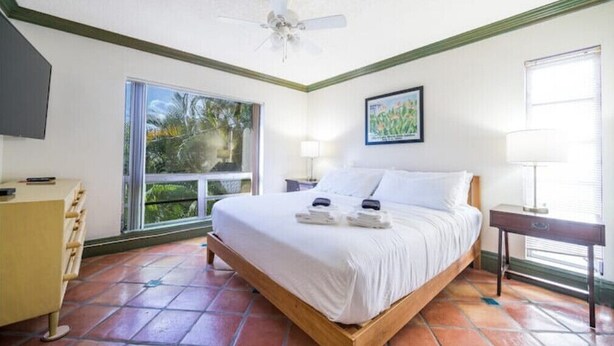 A bedroom with a bed, a desk, a window with a view, a ceiling fan, and a painting on the wall. - 2Bed/2Bath Villa by Golf Course (Lake Worth)