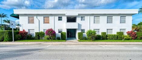 Un edificio moderno de dos pisos con techo plano, ventanas rectangulares y una entrada central.