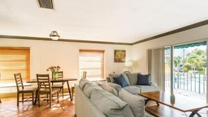 A living room with a sofa, a coffee table, and a dining area with chairs and a table. - 2Bed/2Bath Villa by Golf Course (Lake Worth)