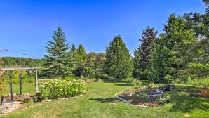 A well-maintained garden with a pergola, various plants, and a clear blue sky. - Cozy Sister Bay Getaway in Converted Barn! (Sister Bay)