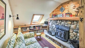 A cozy living room with a stone fireplace, a wooden ceiling, and a skylight. - Cozy Sister Bay Getaway in Converted Barn! (Sister Bay)