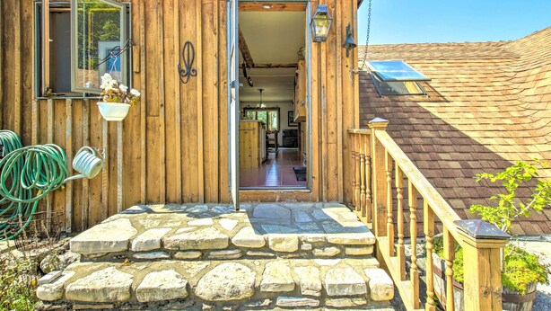 A wooden house with a stone staircase leading to a wooden deck. - Cozy Sister Bay Getaway in Converted Barn! (Sister Bay)