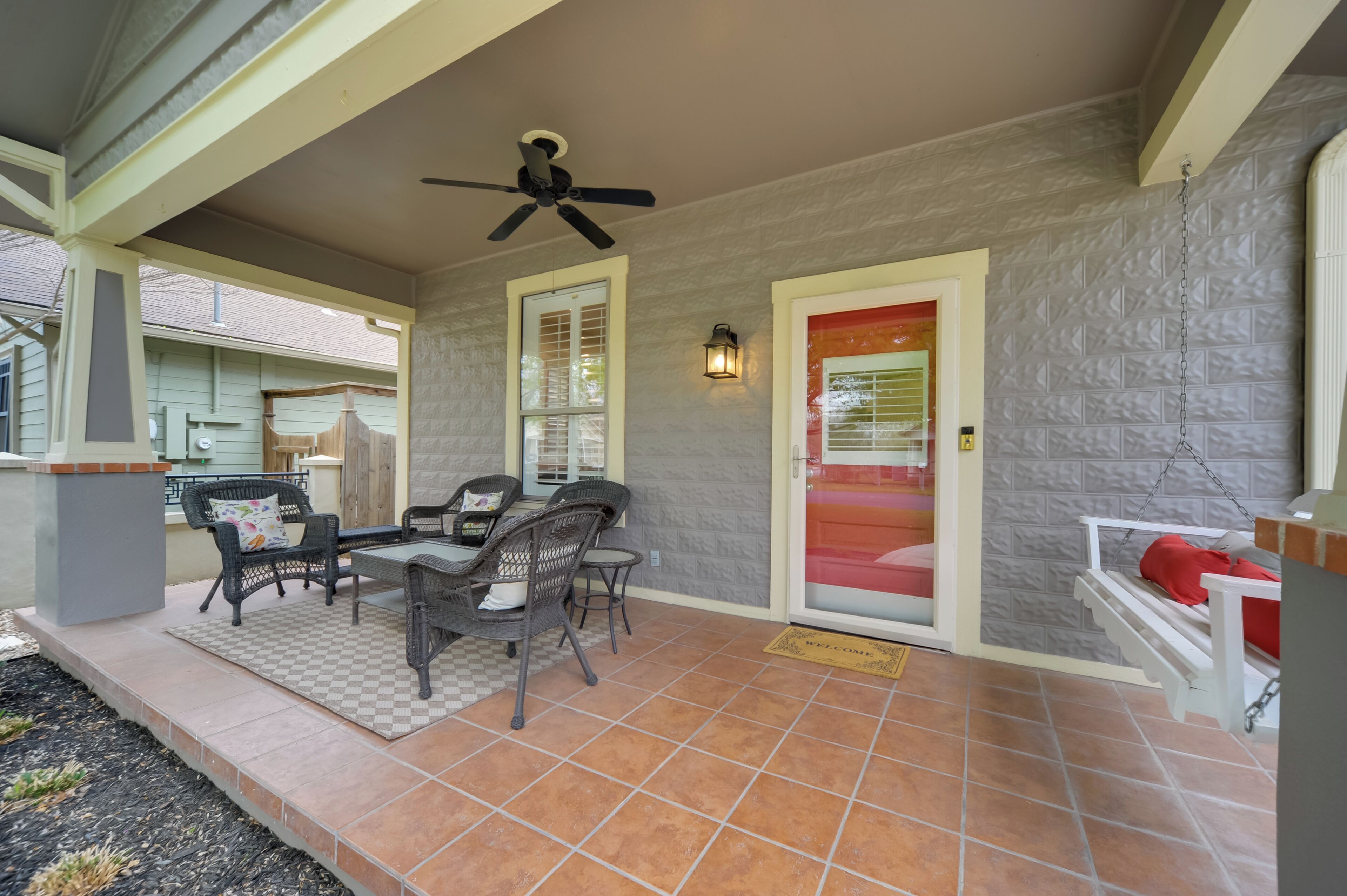 A covered patio with outdoor furniture, a ceiling fan, and a textured wall.
